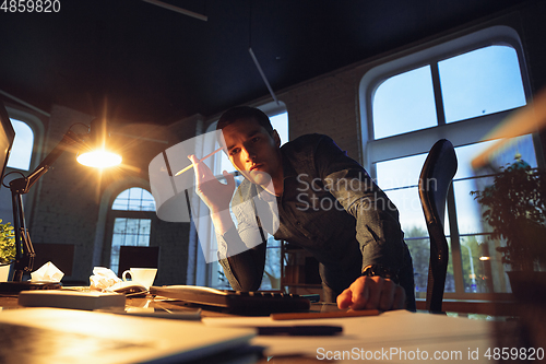 Image of Man working in office alone during coronavirus or COVID-19 quarantine, staying to late night