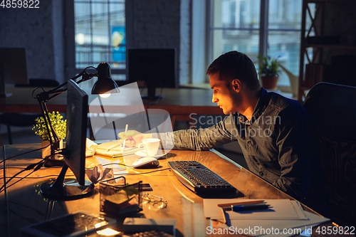 Image of Man working in office alone during coronavirus or COVID-19 quarantine, staying to late night