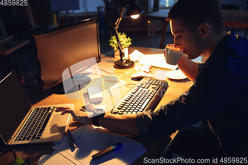 Image of Man working in office alone during coronavirus or COVID-19 quarantine, staying to late night