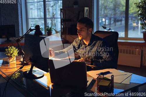 Image of Man working in office alone during coronavirus or COVID-19 quarantine, staying to late night