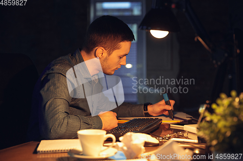 Image of Man working in office alone during coronavirus or COVID-19 quarantine, staying to late night