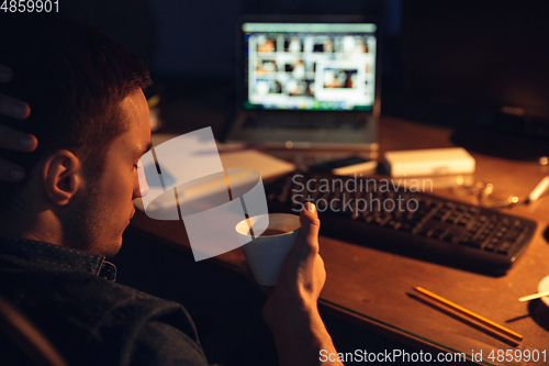 Image of Man working in office alone during coronavirus or COVID-19 quarantine, staying to late night