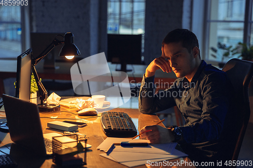 Image of Man working in office alone during coronavirus or COVID-19 quarantine, staying to late night