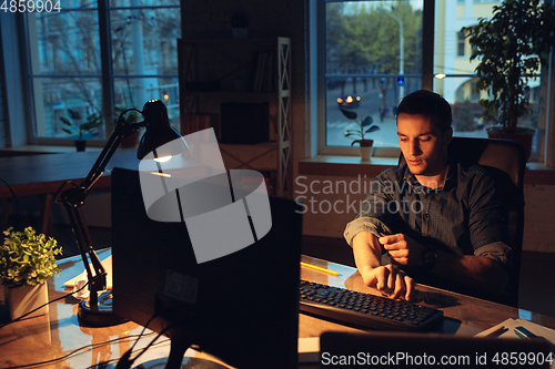 Image of Man working in office alone during coronavirus or COVID-19 quarantine, staying to late night