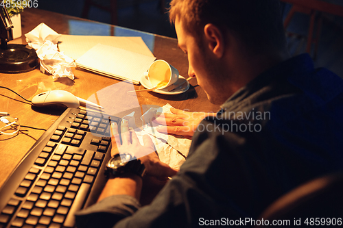Image of Man working in office alone during coronavirus or COVID-19 quarantine, staying to late night