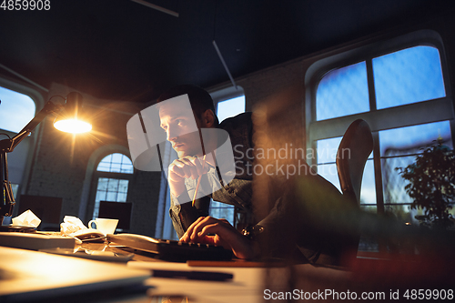 Image of Man working in office alone during coronavirus or COVID-19 quarantine, staying to late night