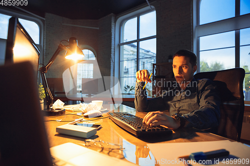 Image of Man working in office alone during coronavirus or COVID-19 quarantine, staying to late night