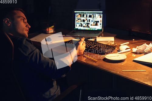 Image of Man working in office alone during coronavirus or COVID-19 quarantine, staying to late night