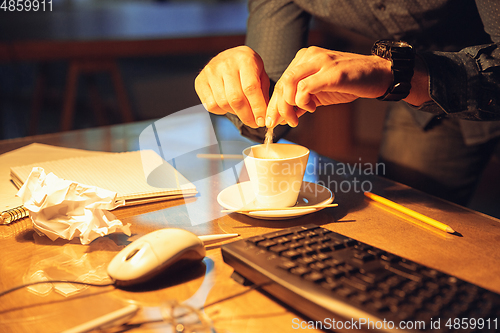 Image of Man working in office alone during coronavirus or COVID-19 quarantine, staying to late night