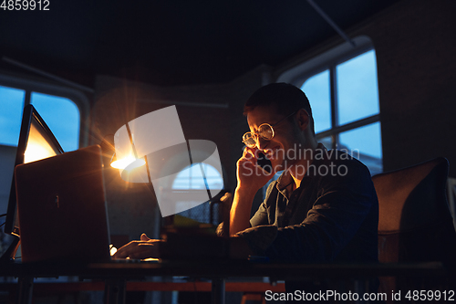 Image of Man working in office alone during coronavirus or COVID-19 quarantine, staying to late night