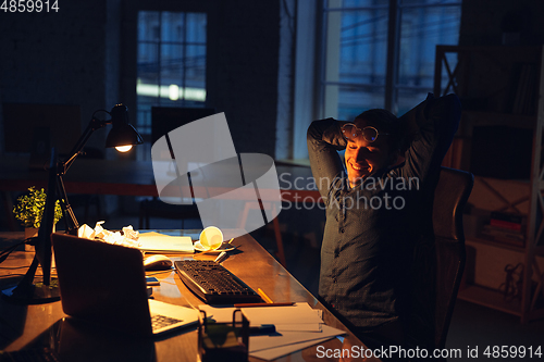 Image of Man working in office alone during coronavirus or COVID-19 quarantine, staying to late night