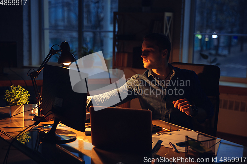 Image of Man working in office alone during coronavirus or COVID-19 quarantine, staying to late night
