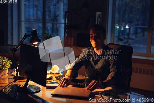 Image of Man working in office alone during coronavirus or COVID-19 quarantine, staying to late night