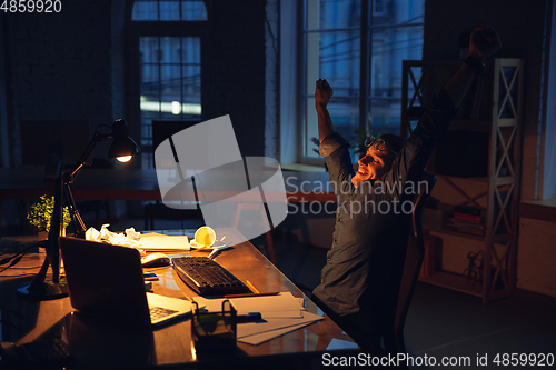 Image of Man working in office alone during coronavirus or COVID-19 quarantine, staying to late night