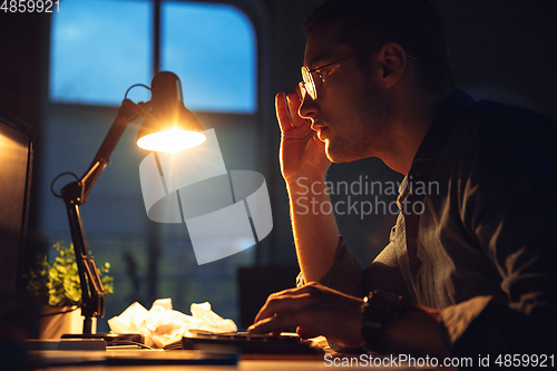 Image of Man working in office alone during coronavirus or COVID-19 quarantine, staying to late night