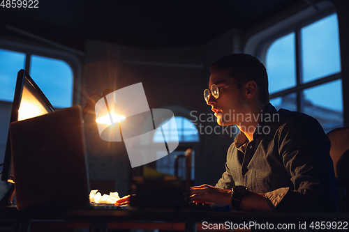 Image of Man working in office alone during coronavirus or COVID-19 quarantine, staying to late night