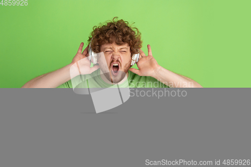 Image of Caucasian young man\'s monochrome portrait on green studio background