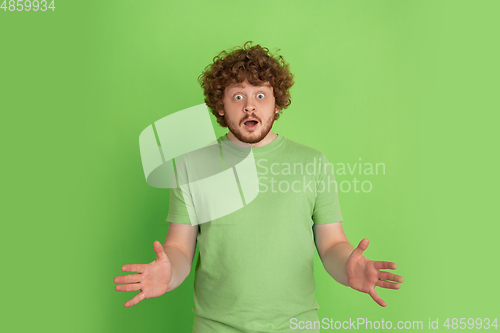 Image of Caucasian young man\'s monochrome portrait on green studio background