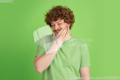 Image of Caucasian young man\'s monochrome portrait on green studio background