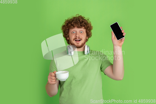 Image of Caucasian young man\'s monochrome portrait on green studio background