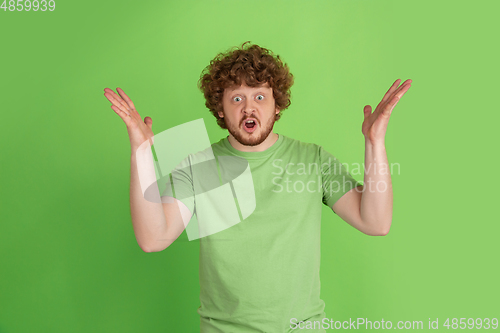 Image of Caucasian young man\'s monochrome portrait on green studio background
