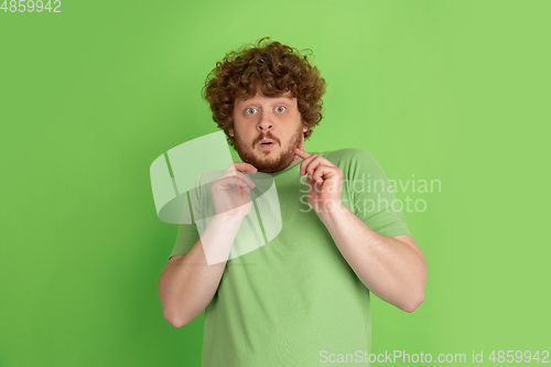 Image of Caucasian young man\'s monochrome portrait on green studio background