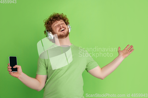 Image of Caucasian young man\'s monochrome portrait on green studio background