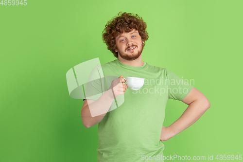 Image of Caucasian young man\'s monochrome portrait on green studio background