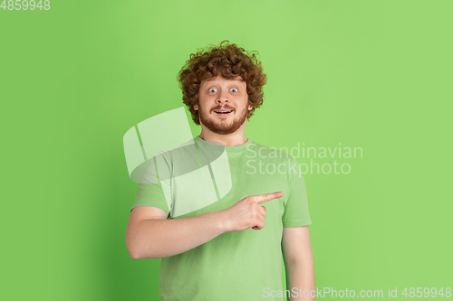 Image of Caucasian young man\'s monochrome portrait on green studio background