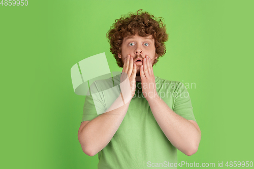 Image of Caucasian young man\'s monochrome portrait on green studio background