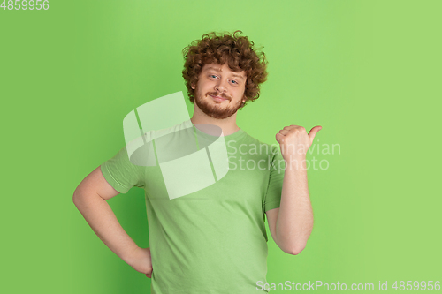 Image of Caucasian young man\'s monochrome portrait on green studio background