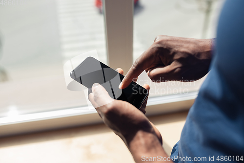 Image of Close up of african-american male hands, working in office