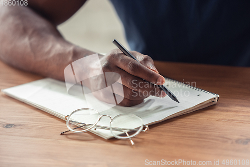 Image of Close up of african-american male hands, working in office