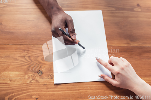 Image of Close up of african-american male and caucasian female hands, working in office