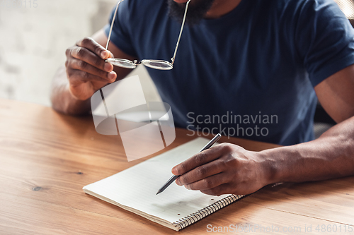 Image of Close up of african-american male hands, working in office