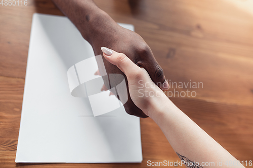 Image of Close up of african-american male and caucasian female hands, working in office