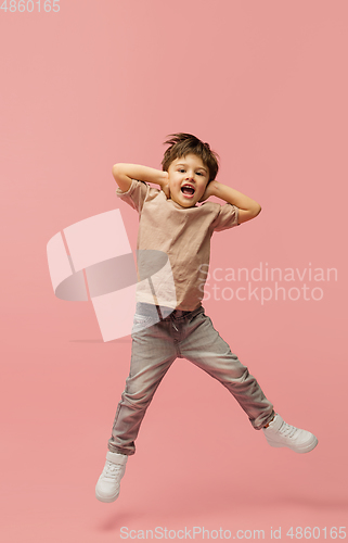 Image of Happy caucasian little boy isolated on pink studio background. Looks happy, cheerful, sincere. Copyspace. Childhood, education, emotions concept