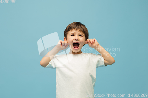 Image of Happy caucasian little boy isolated on blue studio background. Looks happy, cheerful, sincere. Copyspace. Childhood, education, emotions concept