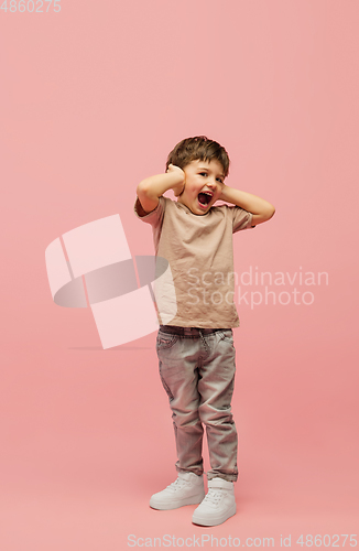 Image of Happy caucasian little boy isolated on pink studio background. Looks happy, cheerful, sincere. Copyspace. Childhood, education, emotions concept