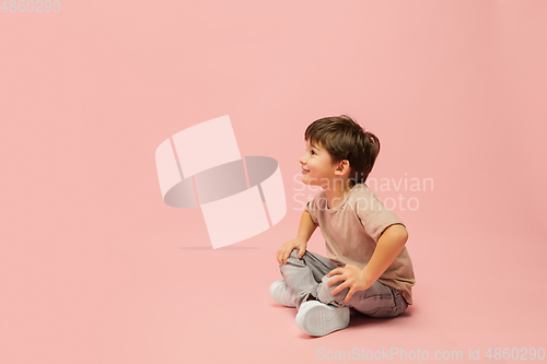 Image of Happy caucasian little boy isolated on pink studio background. Looks happy, cheerful, sincere. Copyspace. Childhood, education, emotions concept