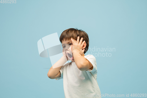 Image of Happy caucasian little boy isolated on blue studio background. Looks happy, cheerful, sincere. Copyspace. Childhood, education, emotions concept