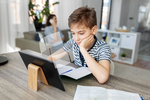 Image of student boy with tablet computer learning at home