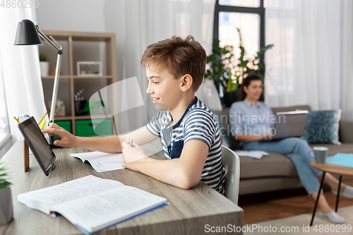 Image of student boy with tablet computer learning at home