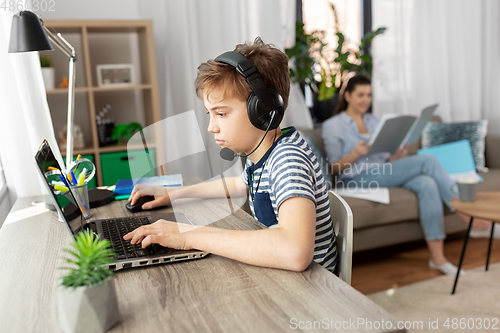 Image of boy with laptop and headphones at home