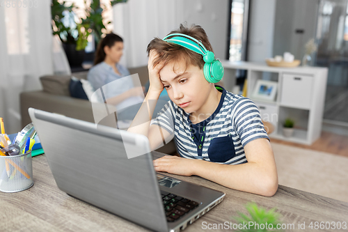 Image of sad boy with laptop and headphones at home