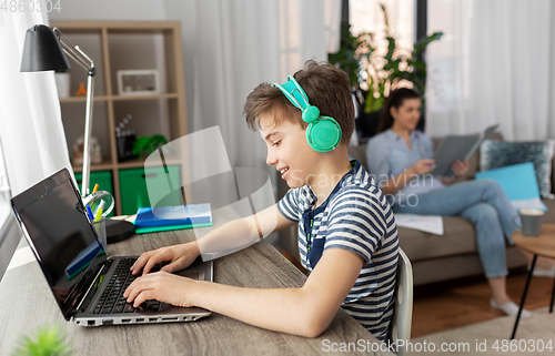 Image of boy with laptop and headphones at home