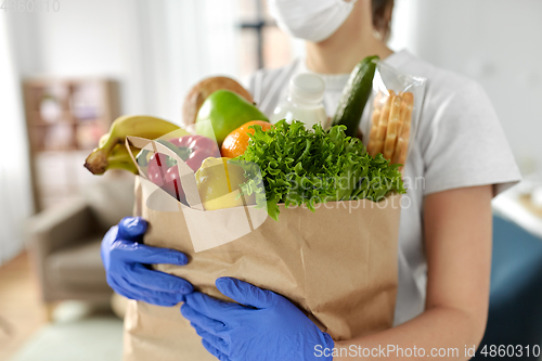 Image of woman in gloves with food in paper bag at home