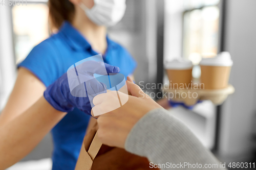 Image of delivery girl in mask giving paper bag to woman