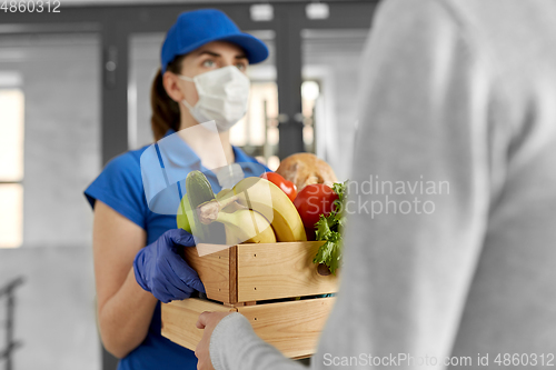 Image of delivery woman in mask giving food to customer