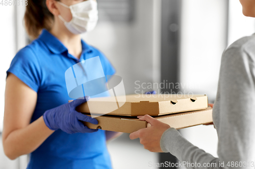 Image of delivery girl in mask giving pizza boxes to woman